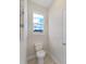 Small powder room featuring a toilet, window view, and light fixtures at 9273 Highland Hills Dr, Hudson, FL 34667