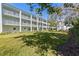 Exterior of building with white balconies and large grassy area shaded by a mature tree at 1706 Belleair Forest Dr # 348, Belleair, FL 33756