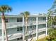 Condo building featuring private balconies, mature palm trees, and well-maintained landscaping at 1706 Belleair Forest Dr # 348, Belleair, FL 33756