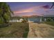 A single-story home at dusk with two-car garage, manicured lawn and mature landscaping provides a welcoming curb appeal at 13614 Evelane Dr, Hudson, FL 34667