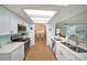 Bright, galley kitchen with white cabinets, stainless steel appliances, and an open view into the dining and living areas at 13614 Evelane Dr, Hudson, FL 34667