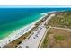 Aerial view of a beautiful beach with clear turquoise waters, sandy shores, and ample parking at 2085 Hunters Glen Dr # 228, Dunedin, FL 34698