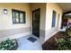 A welcoming entrance with neutral stucco, colorful landscaping, and a black screen door at 2689 Sabal Springs Cir # 103, Clearwater, FL 33761