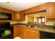 Kitchen with wood cabinets, granite counters, tile backsplash, and modern black appliances at 2689 Sabal Springs Cir # 103, Clearwater, FL 33761