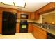 Well-equipped kitchen featuring wood cabinetry, a pass-through window, and modern black appliances at 2689 Sabal Springs Cir # 103, Clearwater, FL 33761