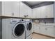 Bright laundry room features white cabinetry, tile floor, counter space and modern appliances at 29924 Rusco Ct, Wesley Chapel, FL 33545
