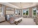 Spacious main bedroom with tray ceilings, a chandelier, and large windows with a view of nature at 29924 Rusco Ct, Wesley Chapel, FL 33545