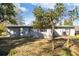 View of the rear of a gray house with a metal roof and green lawn area at 306 Midwood Dr, Plant City, FL 33566