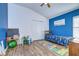 Bright bedroom with wood-look flooring, blue accent wall, and decor at 3133 Beaver Pond Trl, Valrico, FL 33596