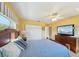 Bright bedroom featuring yellow walls, hardwood floors, closet, ceiling fan, and a comfortable-looking bed at 334 Club Manor Dr, Sun City Center, FL 33573