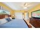 Bright bedroom featuring yellow walls, hardwood floors, closet, ceiling fan, and a comfortable-looking bed at 334 Club Manor Dr, Sun City Center, FL 33573