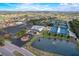 Aerial view of a community center featuring tennis courts, a large parking area, and a decorative pond with fountain at 334 Club Manor Dr, Sun City Center, FL 33573