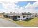 Exterior view showcasing the attached two-car garage, white exterior, screened lanai and well-manicured lawn at 334 Club Manor Dr, Sun City Center, FL 33573