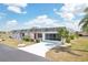 Desirable one-story home with bright white brick, red door, screened garage, palm trees and a white concrete driveway at 334 Club Manor Dr, Sun City Center, FL 33573