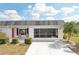 Inviting single-story home with a white brick facade, a red front door, and a screened-in garage with a white driveway at 334 Club Manor Dr, Sun City Center, FL 33573