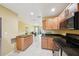 Well-lit kitchen featuring tile floors, wooden cabinets, and modern black appliances at 334 Club Manor Dr, Sun City Center, FL 33573