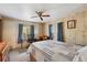 Bedroom featuring wood-paneled walls, a ceiling fan, and a bright window with blue curtains at 37841 Mission Hills Ave, Zephyrhills, FL 33541