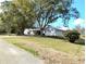 Property featuring a well-maintained lawn, mature trees, and an attached garage for convenience and curb appeal at 39349 & 39343 Rusbe Dr, Zephyrhills, FL 33540