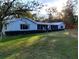 Sprawling single-story home with white exterior, screened porch, and lush green lawn at 39349 & 39343 Rusbe Dr, Zephyrhills, FL 33540