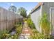 View of the side of the outbuilding, with a fence and a path lined with plants at 4408 W Lackland Pl, Tampa, FL 33616