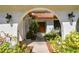 Arched entryway with beautiful lush landscaping leads to the charming front door framed by sconces, and a red tile roof at 4609 W San Miguel St, Tampa, FL 33629