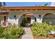 Charming front entrance showcasing a tile roof, an arched entryway, lush landscaping, and decorative wall sconces at 4609 W San Miguel St, Tampa, FL 33629