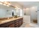 Well-lit bathroom with a dual sink vanity, large mirror, and walk-in shower at 5566 Silver Sun Dr, Apollo Beach, FL 33572