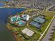 Aerial view highlights community amenities: pools, tennis courts, a basketball court, and a clubhouse by a lake at 5566 Silver Sun Dr, Apollo Beach, FL 33572
