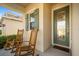 Cozy front porch with two rocking chairs, a decorative front door and lush plants at 5566 Silver Sun Dr, Apollo Beach, FL 33572