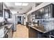 Open kitchen featuring stainless steel appliances, granite countertops, dark cabinets, tile backsplash and skylights at 7911 Floradora Dr, New Port Richey, FL 34654