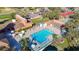Aerial view of a pool, lounge chairs with umbrellas, and the clubhouse surrounded by trees, green space and nearby tennis courts at 8024 Feather Ct # D, Hudson, FL 34667