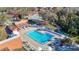 Aerial view of a community pool with lounge chairs, umbrellas, a walking path, and tennis and basketball courts nearby at 8024 Feather Ct # D, Hudson, FL 34667