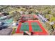 Aerial view of tennis and pickleball courts surrounded by lush landscaping with a clubhouse and pool in the distance at 8024 Feather Ct # D, Hudson, FL 34667