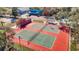 Aerial view of tennis courts with mature trees, with parking, nearby buildings and green space surrounding the courts at 8024 Feather Ct # D, Hudson, FL 34667