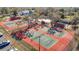 Aerial view of multiple tennis courts, mature trees, with parking, nearby buildings and green space surrounding the courts at 8024 Feather Ct # D, Hudson, FL 34667
