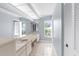 Bright bathroom with double vanity, large mirror, neutral tile flooring, and natural light at 8701 Braxton Dr, Hudson, FL 34667