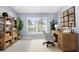 Stylish home office featuring natural wood desk, shelving, light gray walls, and large window with outdoor views at 8701 Braxton Dr, Hudson, FL 34667