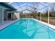 Inviting screened-in pool with clear blue water, surrounded by a patio and lush greenery at 8701 Braxton Dr, Hudson, FL 34667