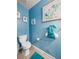 Cozy bathroom with blue walls, tiled floors, toilet, and towel rack, creating a refreshing atmosphere at 17308 Holly Well Ave, Wimauma, FL 33598