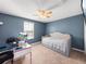 This bedroom features blue walls, a ceiling fan, a window, a bed, and a desk with a computer at 17308 Holly Well Ave, Wimauma, FL 33598