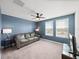 Upstairs living room featuring large windows, a ceiling fan, and tan carpeting at 17308 Holly Well Ave, Wimauma, FL 33598