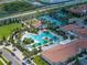 Aerial view of a community pool, tennis courts, and lush tropical landscaping at 17308 Holly Well Ave, Wimauma, FL 33598