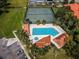 Aerial view of the community pool with spa, cabanas, tennis courts, and palm trees at 1003 Hammock Pine Blvd # 1003, Clearwater, FL 33761