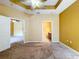 Spacious carpeted bedroom with a ceiling fan and access to a bathroom and closet at 11212 Port Douglas Dr, New Port Richey, FL 34654