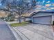 Street view of townhomes featuring well-maintained lawns, mature trees, and attached two-car garages with wide driveways at 11212 Port Douglas Dr, New Port Richey, FL 34654