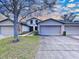 Charming townhome featuring a well-maintained lawn, mature trees, and an attached two-car garage with a wide driveway at 11212 Port Douglas Dr, New Port Richey, FL 34654