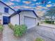 Close up of townhome featuring a well-maintained lawn, landscaping, and an attached two-car garage with a wide driveway at 11212 Port Douglas Dr, New Port Richey, FL 34654