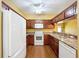 Close up of kitchen featuring white appliances, wood cabinets, granite countertops, and wood flooring at 11212 Port Douglas Dr, New Port Richey, FL 34654