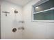 Modern bathroom shower featuring white tiles, a shower head, and convenient shelving at 1166 Granada St, Clearwater, FL 33755