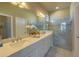 Bright bathroom featuring a double vanity and glass enclosed shower with marble surround at 14466 Pioneer Ridge Dr, Hudson, FL 34667